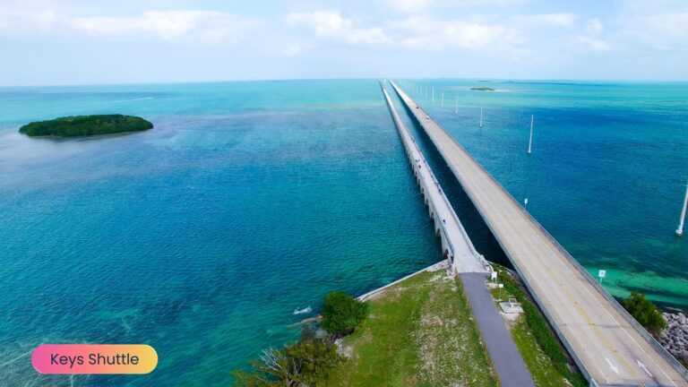 A sleek black Keys Shuttle luxury van driving along the scenic Overseas Highway with bright blue ocean waters and island lush greenery surrounding the road.